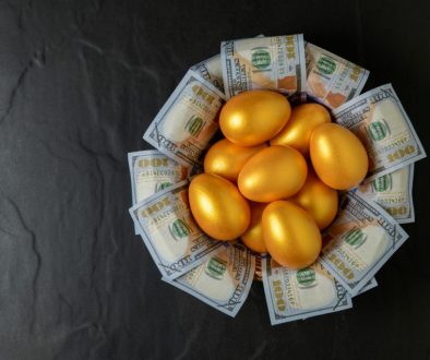 golden eggs and dollars in a basket on black, top view